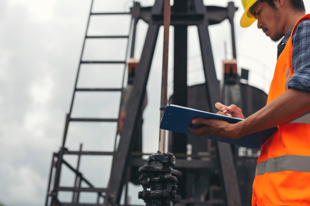 workers standing and checking beside working oil pumps.